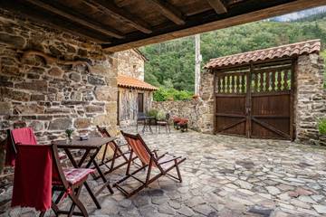 Porche rústico con vigas de madera y zona de estar exterior en Las Merindades